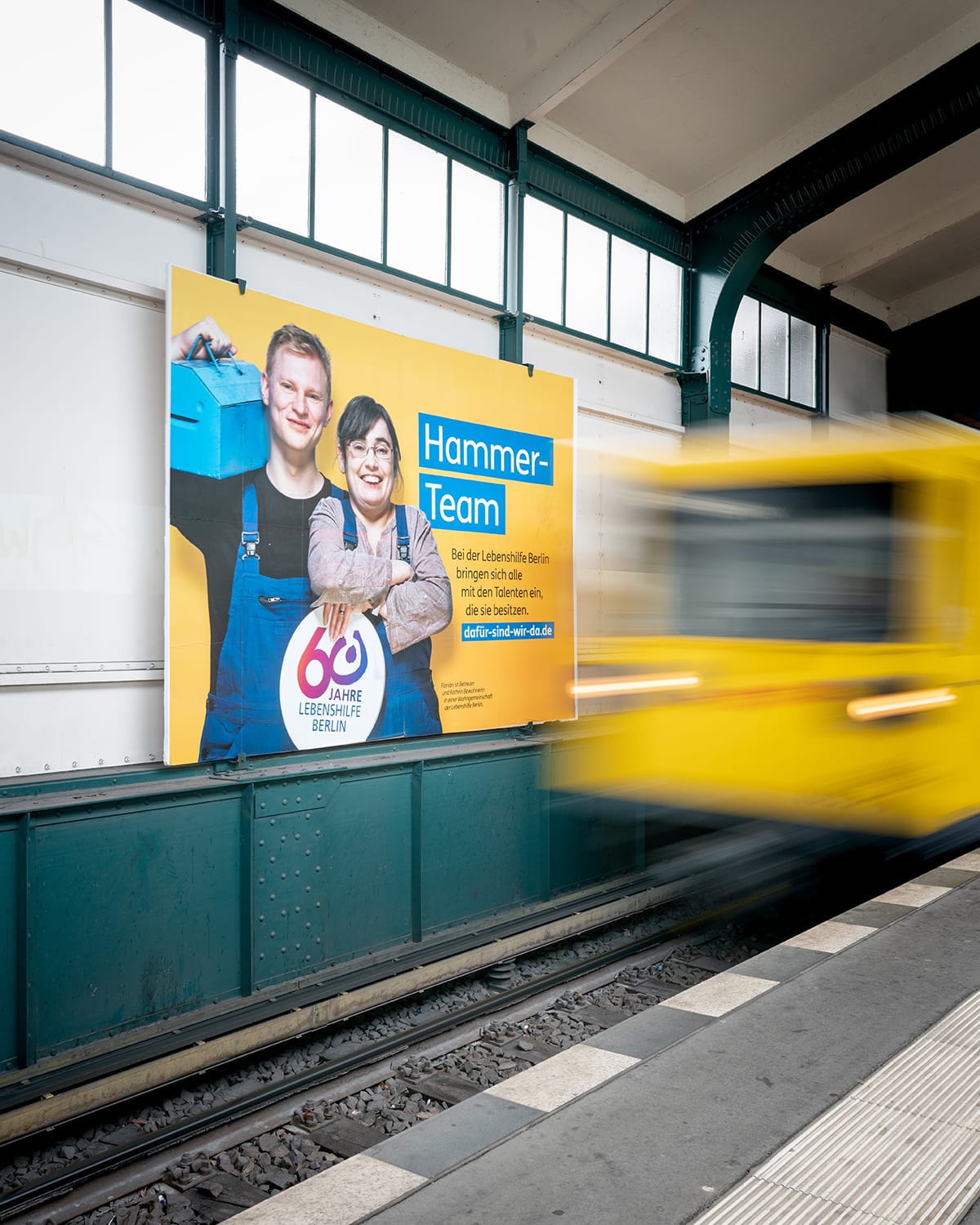 Werbeplakat der Lebenshilfe in einem Berliner U-Bahnhof. Motiv „Hammerteam“.